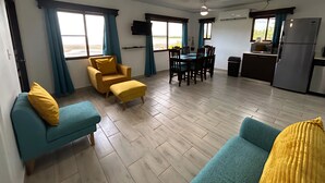 A spacious living area with a sofa, ottoman, and dining table.