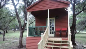 A small wooden cabin with a porch and steps leading to a door. - Hansel & Gretel Charming Cabin @ HomeAway Ranch & NoahSanctuary - Pet friendly! (Boerne)