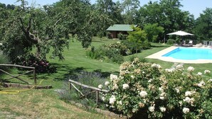 A backyard with a swimming pool, a wooden deck, and a house.