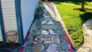 Un sendero de mosaicos que conduce a una casa con un aro de baloncesto a la izquierda.