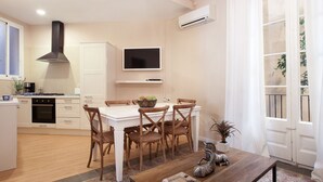 A modern kitchen with white cabinets, a black stove, and a dining area with wooden chairs and a white table.