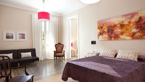 A bedroom with a large bed, a sofa, a chair, and a painting on the wall.
