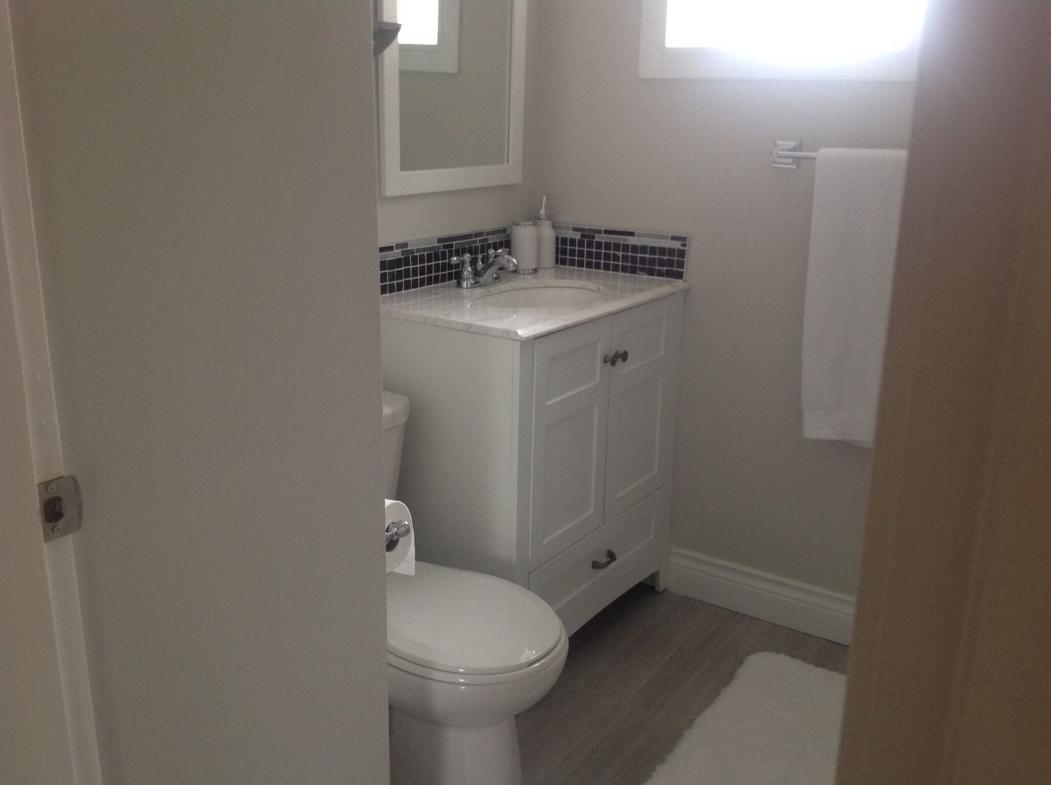 Une petite salle de bain propre, équipée de toilettes, d’un lavabo et d’un miroir.