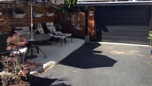 Une terrasse extérieure avec une table et des chaises, une clôture décorative et une porte de garage.