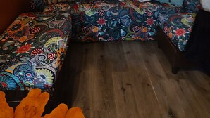 Una sala de estar acogedora con suelo de madera, un conjunto de sofás coloridos y un cuadro en la pared.