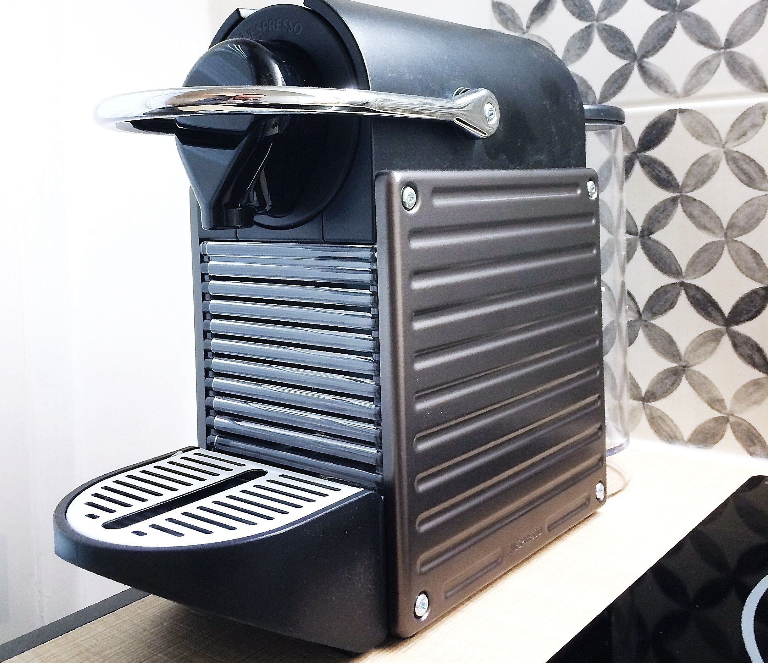 A coffee machine with a black and silver design, a drip tray, and a control panel.