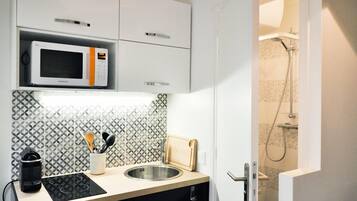 Een moderne keuken met een magnetron, spoelbak en houten snijplank.