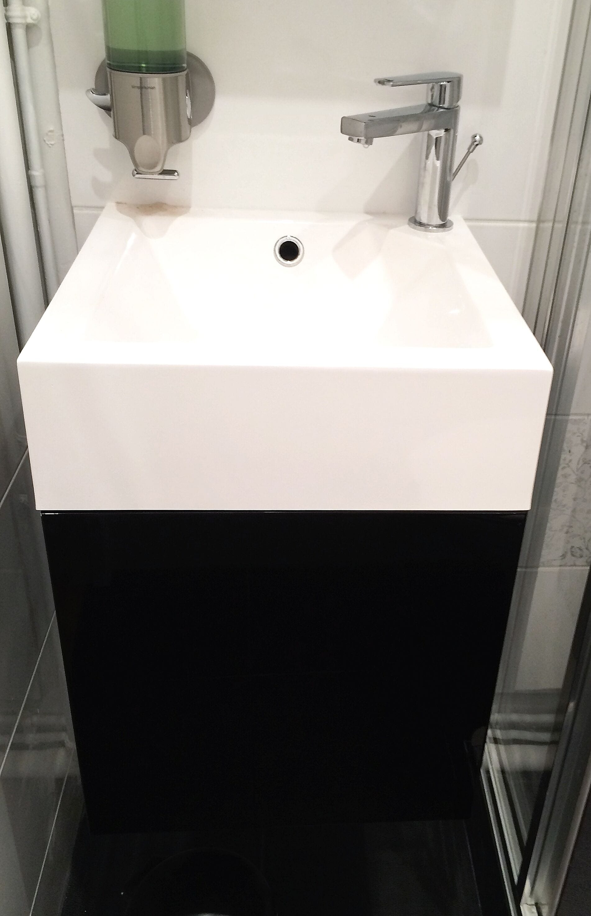 A bathroom with a white sink, a chrome faucet, and a green soap dispenser.