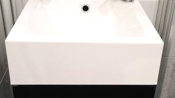 A bathroom with a white sink, a chrome faucet, and a green soap dispenser.