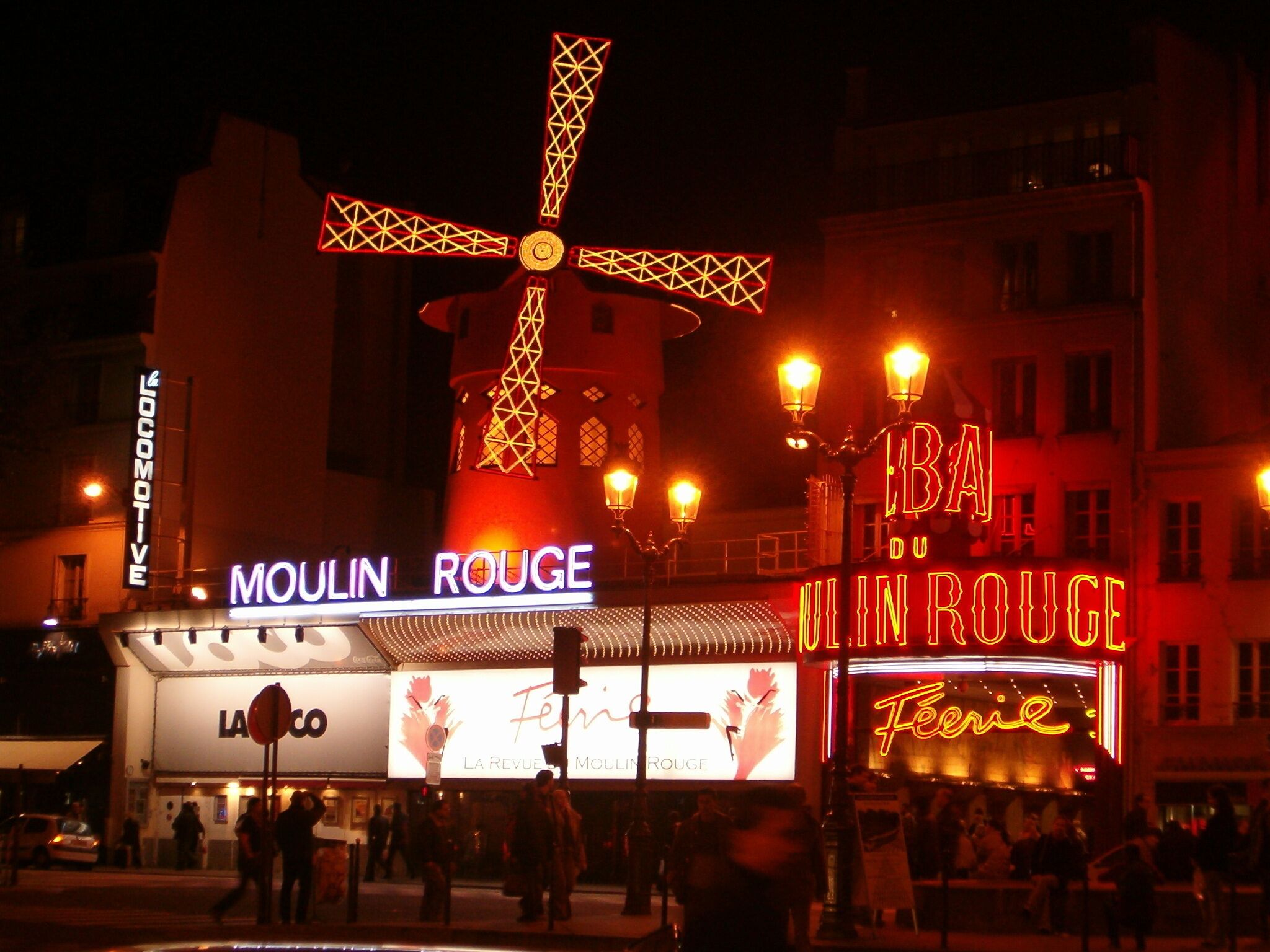 En bygning med oplyste skilte, der viser teksten "Moulin Rouge" og "Feerie".