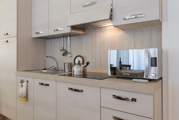 A modern kitchen with a built-in microwave, kettle, and stainless steel sink. - Leopolda Dream  Home (Firenze)