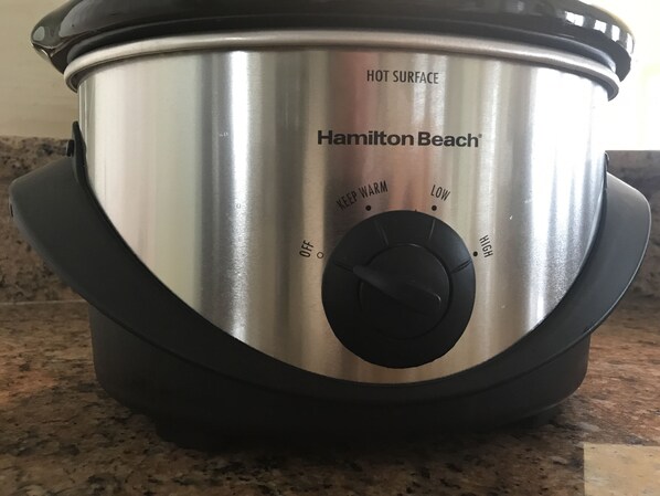A stainless steel Hamilton Beach slow cooker with a black lid and control knob.