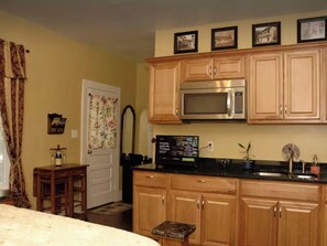 A kitchen with wooden cabinets, a stainless steel microwave, and a black countertop.