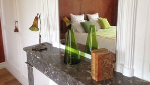 Une chambre à coucher comprenant un lit, des oreillers, une table de chevet et des objets décoratifs, notamment des vases en verre vert et un livre.