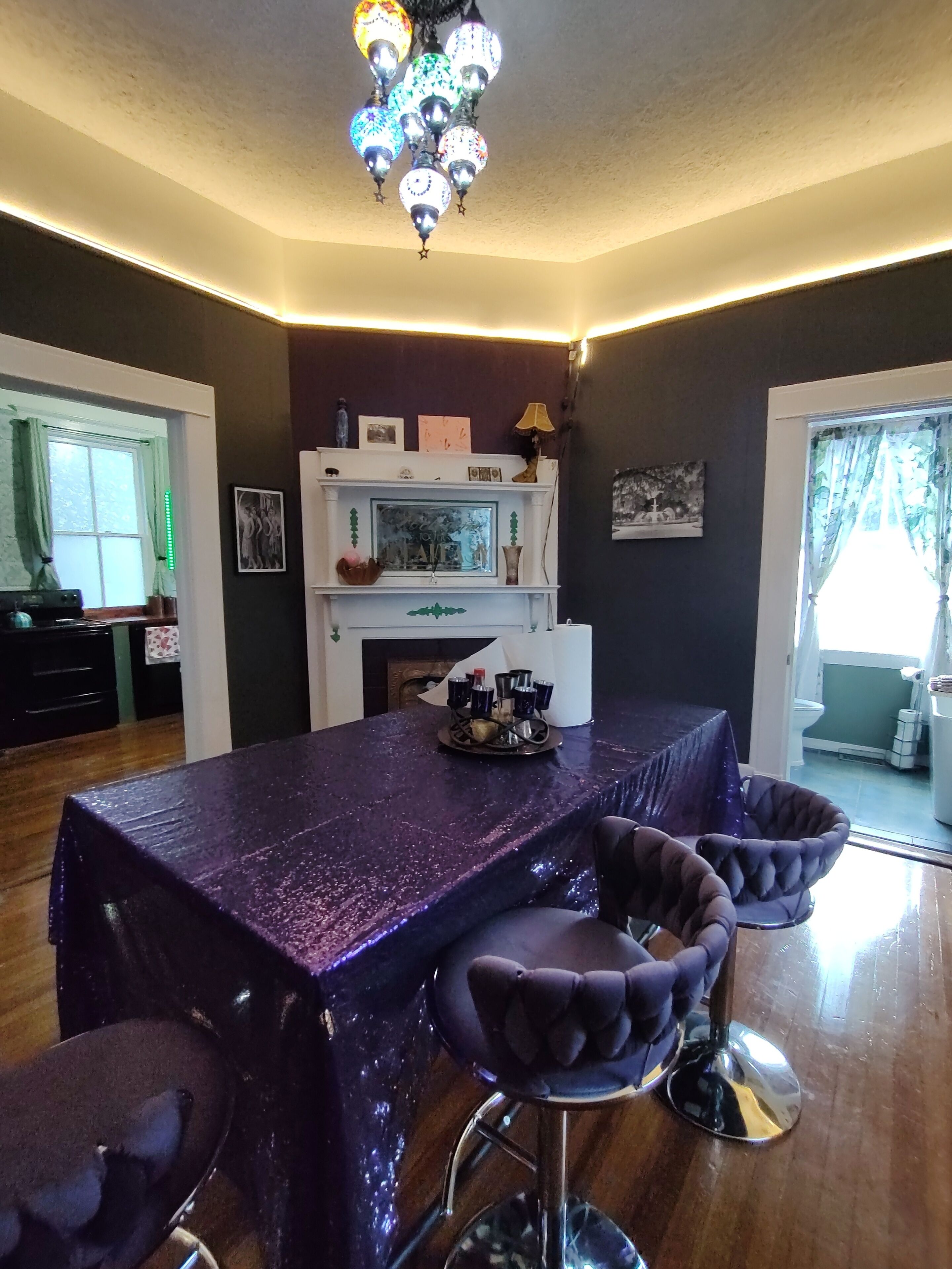 A dining area with a purple tablecloth, a chandelier, and a fireplace.