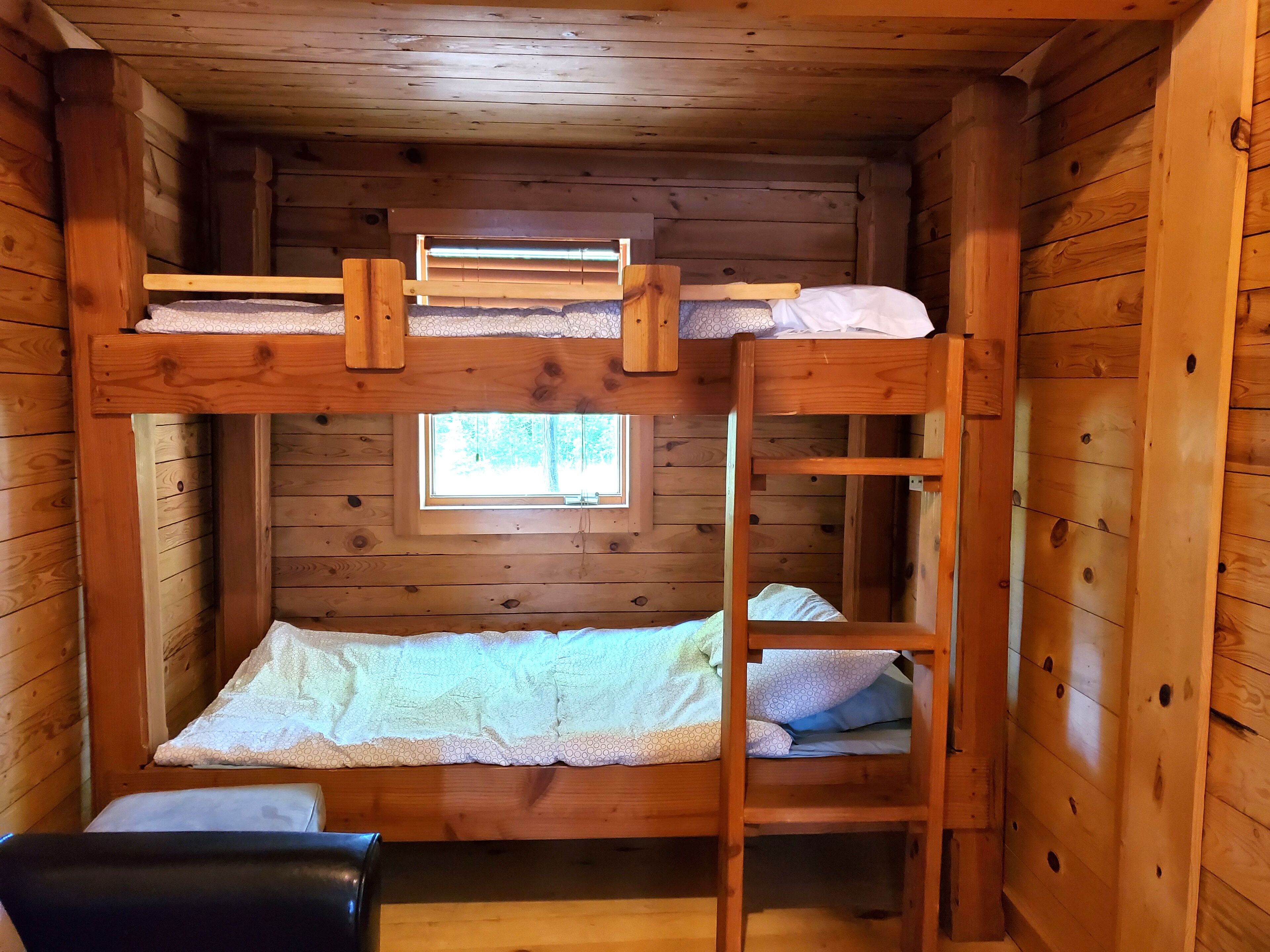 Dormitorio con literas, paredes de madera y ventana.