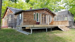 Een houten chalet met een veranda, grote ramen en een schoorsteen.