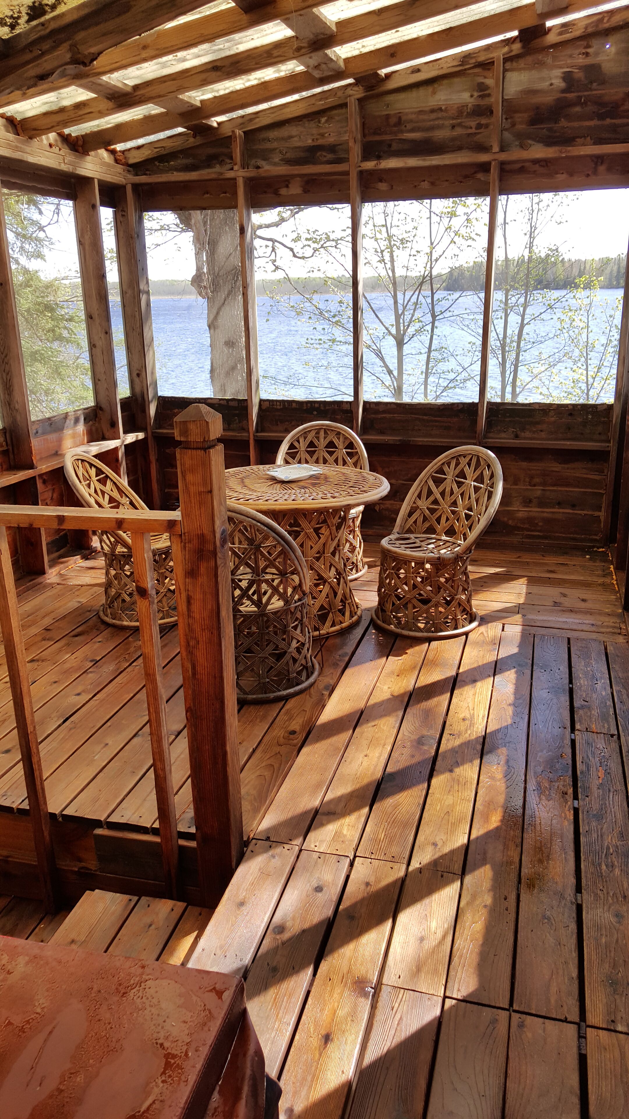A wooden deck with wicker furniture and a view of a lake.