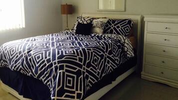A bedroom with a bed, a dresser, and a framed picture on the wall.