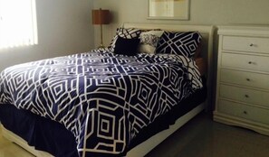Un dormitorio con cama, cómoda y un cuadro en la pared.