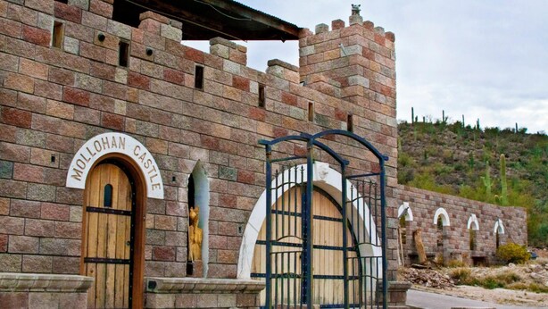 A historic building labeled "Mollohan Castle" with wooden doors and a metal gate.