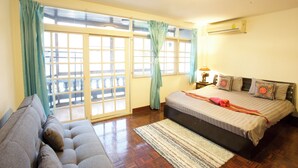 Une chambre avec un lit, un canapé, une fenêtre avec des rideaux et un appareil de climatisation.
