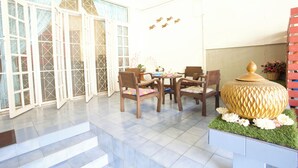 Une vaste terrasse dotée d’un espace repas, d’un vase décoratif et d’un escalier menant à un niveau supérieur.