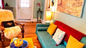 Una sala de estar acogedora con un sofá color turquesa, piso de madera y una puerta con ventana.