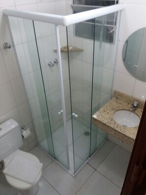 Une salle de bain dotée d’une douche à parois de verre, de toilettes et d’un lavabo avec un plan de travail en granit.