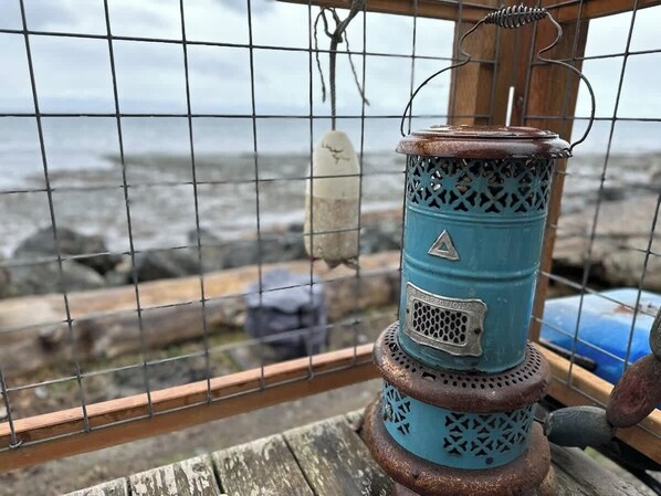 Un farol de metal azul con una señal de advertencia triangular, un panel de malla y un asa, sobre una superficie de madera.