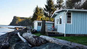 A coastal cabin with a wooden deck and a view of the ocean.