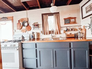 Una cocina con estufa, fregadero y encimera de madera.