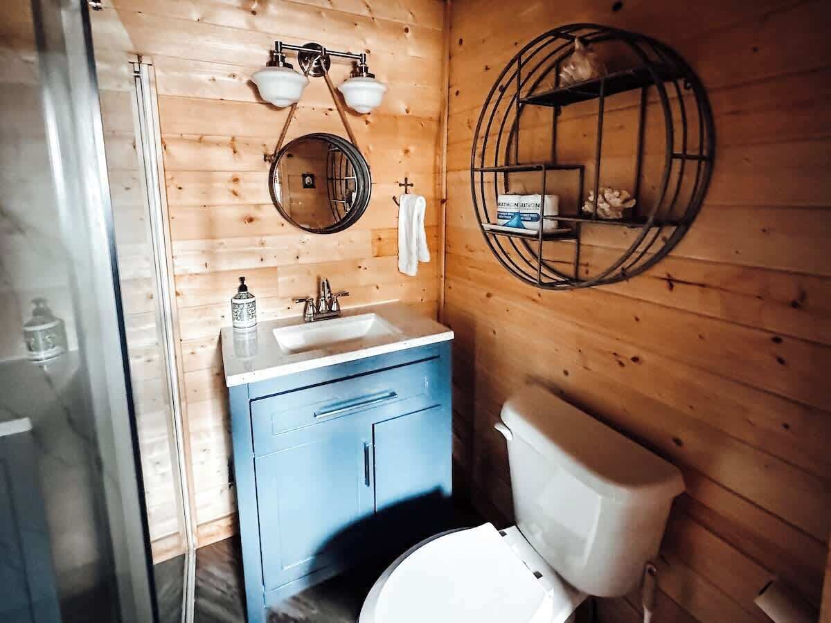Puisesta mökistä löytyvä kylpyhuone, jossa on pesuallas, wc ja peili.