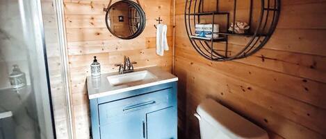 Ein Badezimmer einer Holzhütte mit Waschbecken, Toilette und Spiegel.