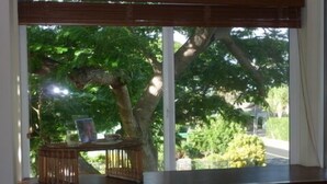 Een kamer met een groot raam met uitzicht op een tuin met bomen en een pad.