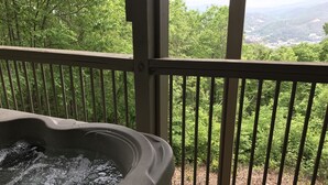 Ein Whirlpool mit Blick auf eine bewaldete Landschaft und entfernte Gebäude.