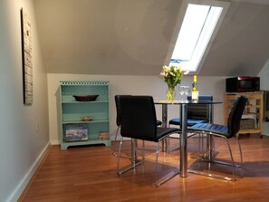Ein Essbereich mit Tisch, Stühlen, einer Vase mit Blumen und einem Regal mit Dekoration.