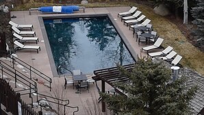 Ein rechteckiger Pool mit Liegestühlen und Tischen darum.