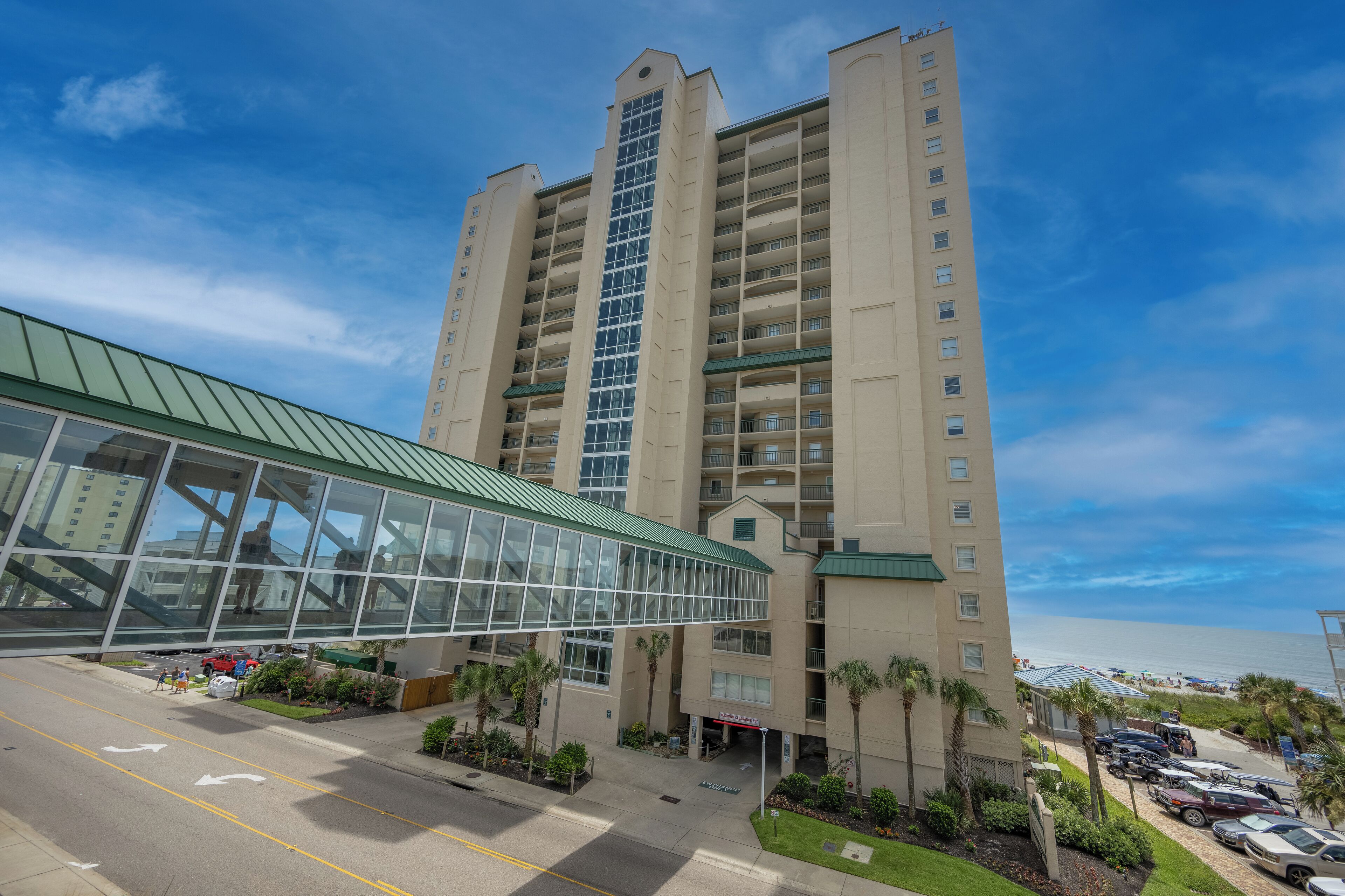 A multi-story hotel with a glass entrance and a parking lot.