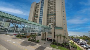 A multi-story hotel with a glass entrance and a parking lot.