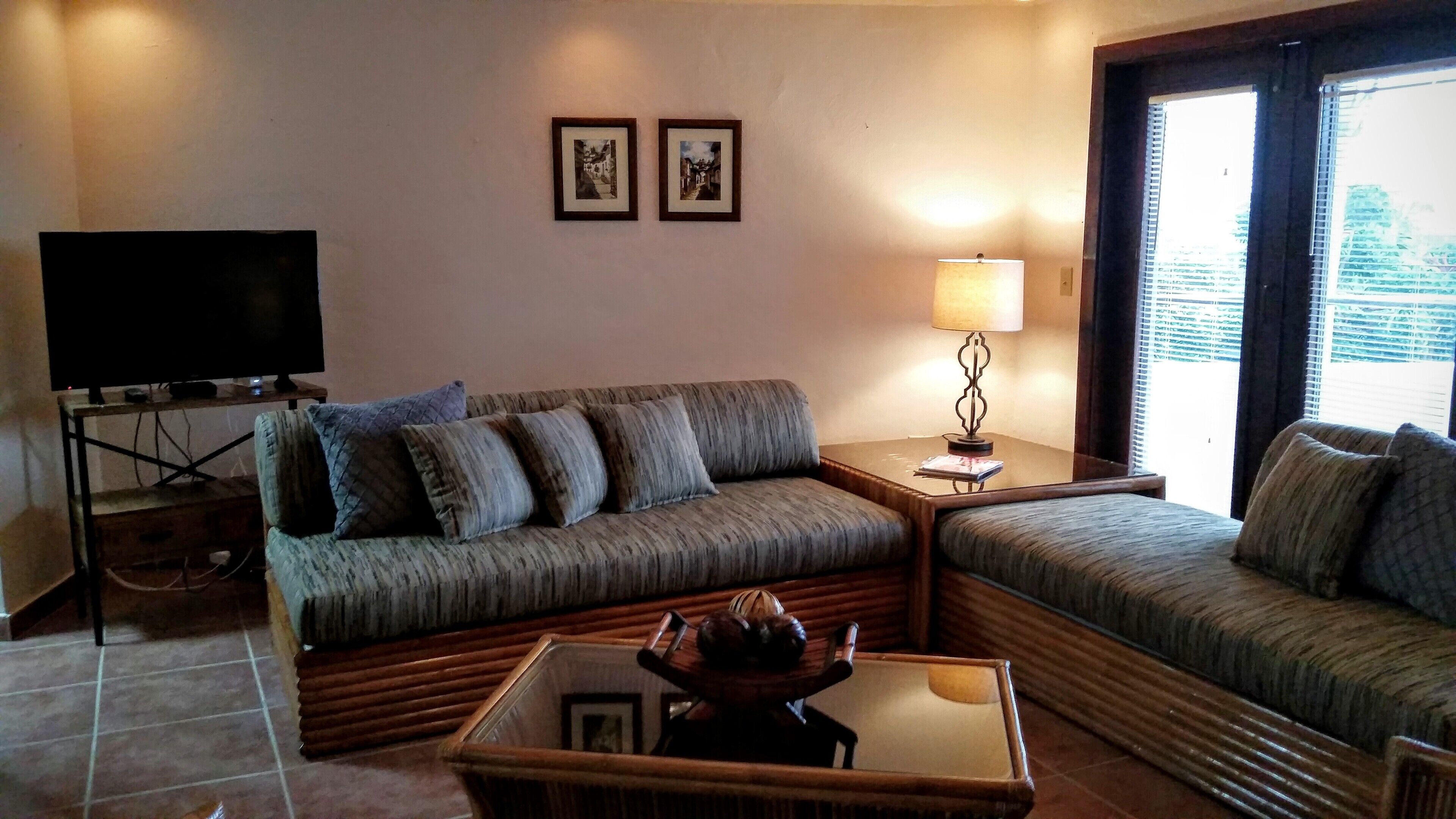 Un salon avec un canapé, une table basse, un téléviseur et une lampe.