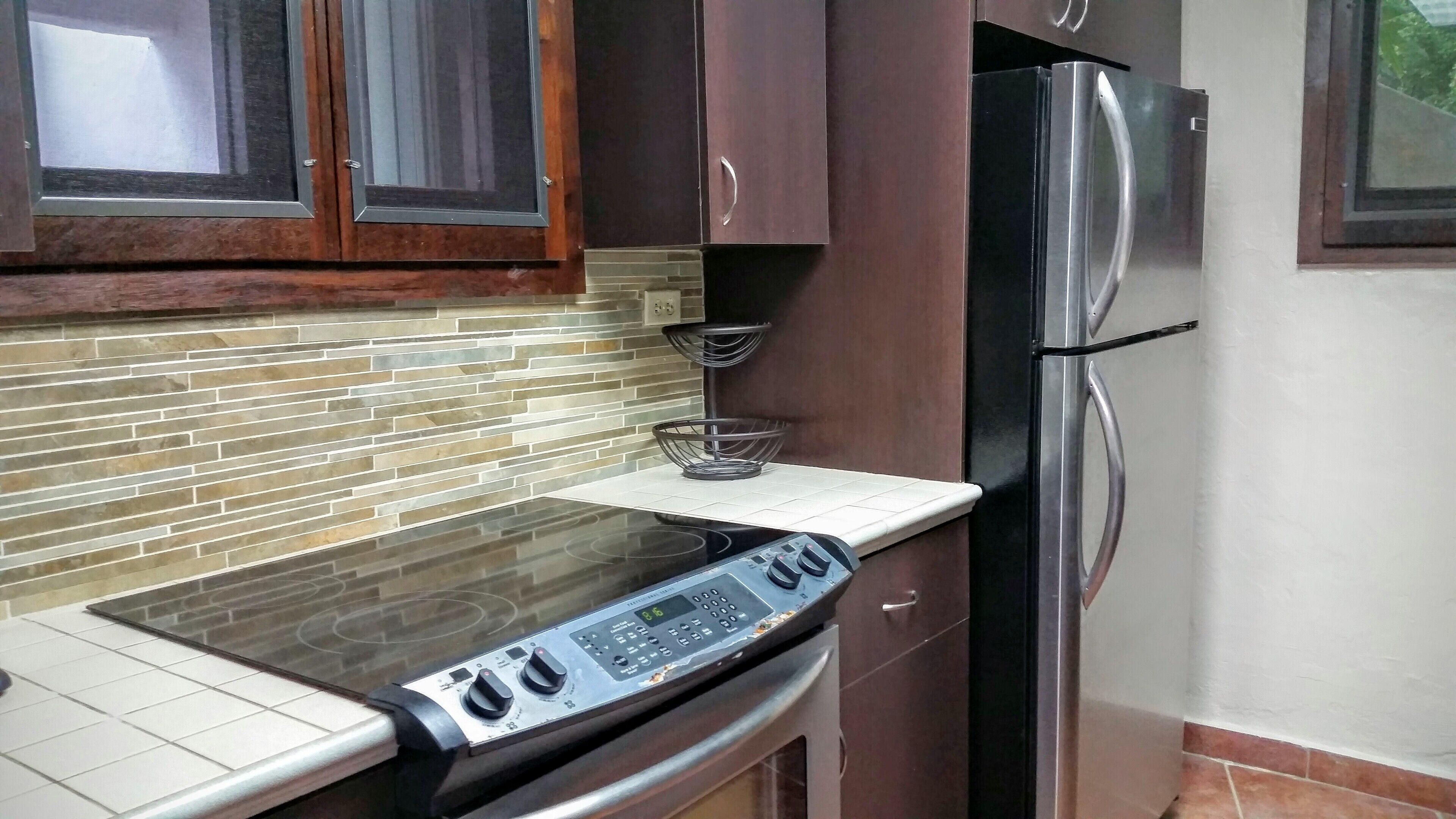 A kitchen with a built-in oven, a stainless steel refrigerator, and a tiled backsplash.