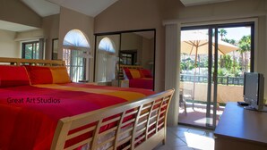 Une chambre d’hôtel dotée d’un grand lit, d’un bureau avec un ordinateur et d’une porte-fenêtre coulissante donnant sur un balcon aménagé avec du mobilier d’extérieur.