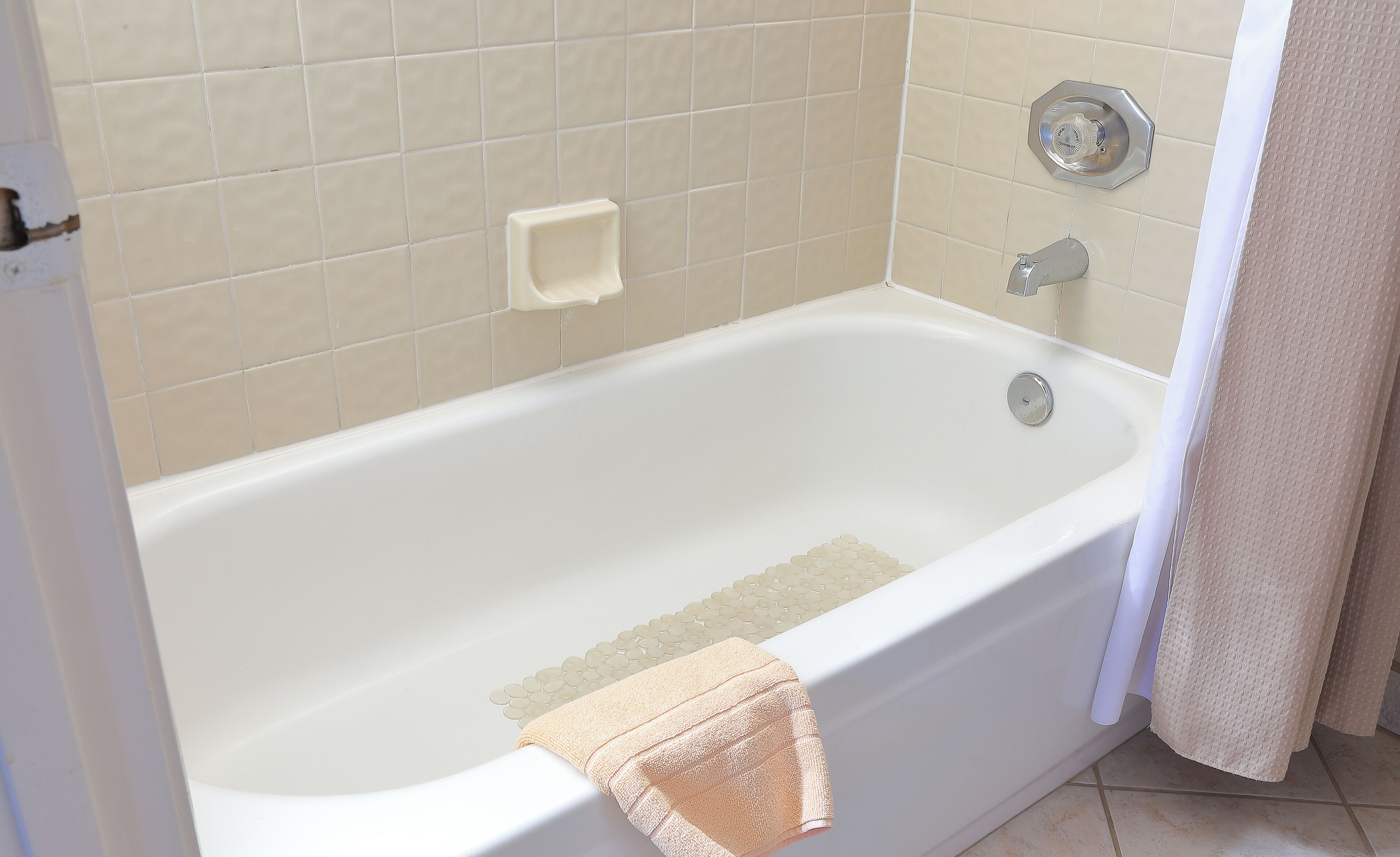 A bathtub with a showerhead, a soap dish, and a towel.