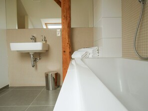 A modern bathroom with a white sink, a bathtub, and a shower.