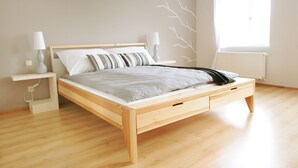 Una cama de madera con cabecera, mesitas de noche y ventana con vistas.