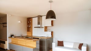 Una cocina moderna con una isla de madera, electrodomésticos de acero inoxidable y un sofá blanco en un amplio salón.