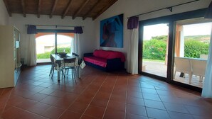 Una habitación con una mesa de comedor y sillas, un sofá y un ventanal con cortinas.