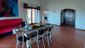 Un comedor con una mesa preparada para cuatro personas, un sofá rojo y un cuadro en la pared.