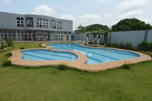 Un edificio moderno con ventanas amplias y una piscina con sillas de descanso.